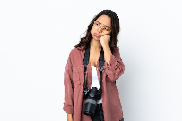 Giovane donna del fotografo sopra la parete bianca isolata con l'espressione stanca e annoiata