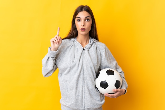 Giovane donna del giocatore di football americano isolata sulla parete gialla che pensa un'idea che punta il dito verso l'alto