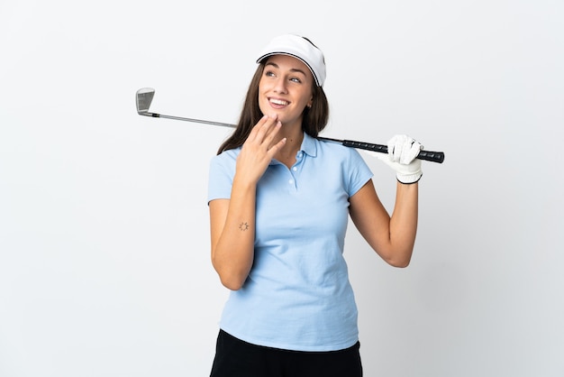 Giovane donna del giocatore di golf sopra fondo bianco isolato che osserva in su mentre sorride