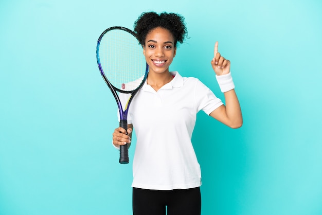Giovane donna del giocatore di tennis isolata su fondo blu che indica una grande idea