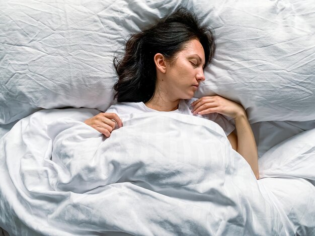 Giovane donna del millennio dorme a casa su lenzuola a righe bianche all'inizio dell'atmosfera mattutina