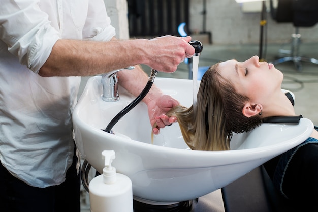 Giovane donna dell'adolescente nel salone di parrucchiere lavare i capelli