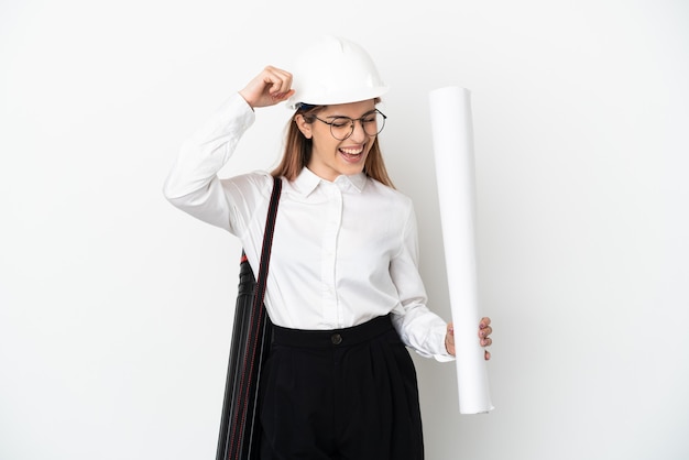 Giovane donna dell'architetto con il casco e che tiene i modelli isolati su fondo bianco che celebra una vittoria