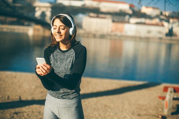 Giovane donna dell&#39;atleta con il telefono cellulare all&#39;aperto