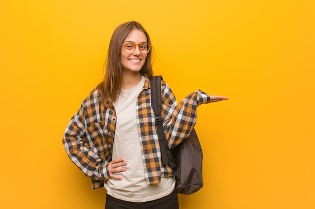 Giovane donna dello studente che tiene qualcosa con la mano