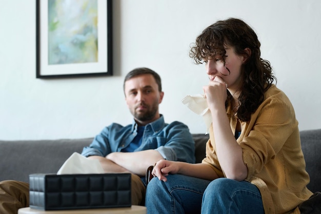 Giovane donna depressa che usa un fazzoletto mentre visita uno psicologo con suo marito