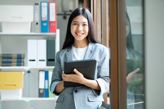 Giovane donna di affari asiatica che lavora all'ufficio facendo uso del computer portatile