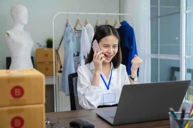 Giovane donna di affari asiatica che lavora allo smartphone ed eccitata per il successo.