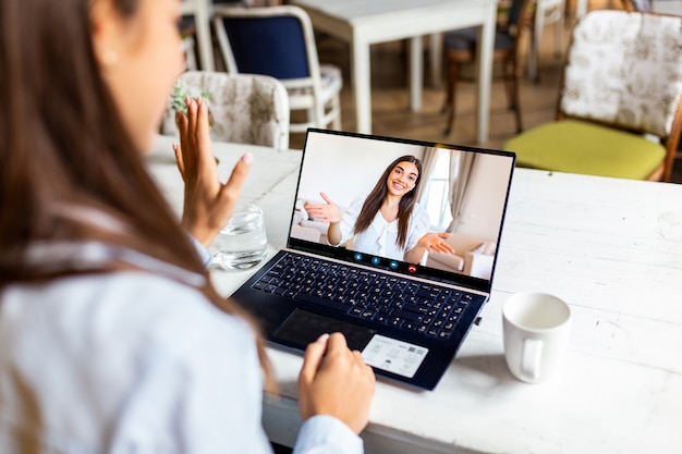 Giovane donna di affari che beve caffè e che utilizza computer portatile nella caffetteria