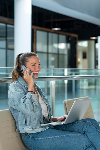 Giovane donna di affari che lavora nell'ufficio moderno che si siede e che usa il computer portatile