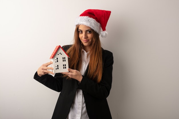 Giovane donna di affari che porta il cappello della Santa che celebra giorno di Natale