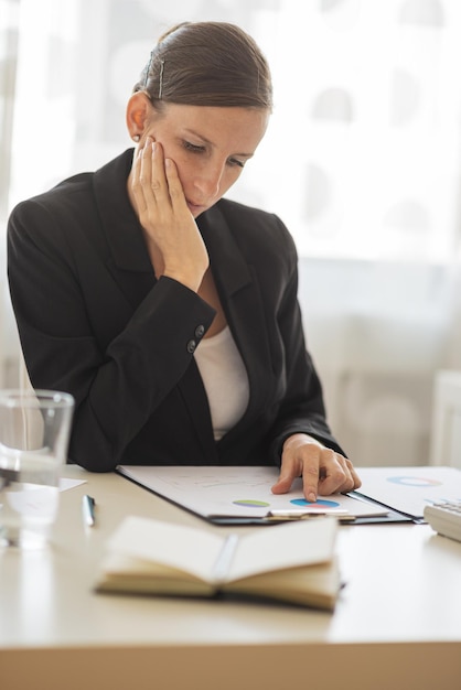 Giovane donna di affari che si siede alla sua scrivania di lavoro