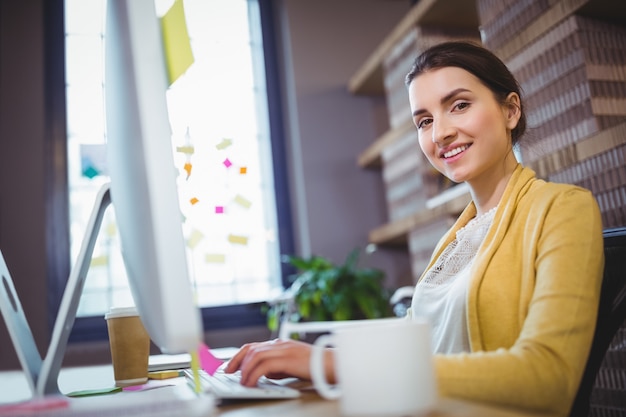 Giovane donna di affari creativa che lavora allo scrittorio del computer