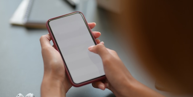 Giovane donna di affari del colpo potato che tiene lo smartphone dello schermo in bianco mentre lavorando