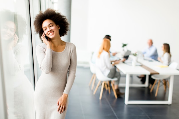 Giovane donna di affari dell&#39;afroamericano che per mezzo del telefono cellulare