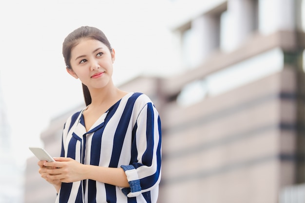 Giovane donna di affari di stile di vita all&#39;aperto che considera smartphone