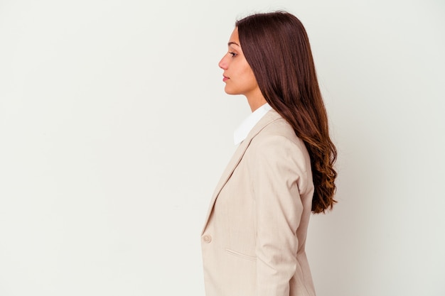 Giovane donna di affari isolata sulla parete bianca che guarda a sinistra, posa lateralmente