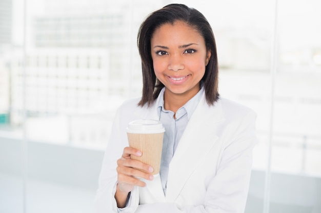 Giovane donna di affari mora adorabile che tiene una tazza di caffè