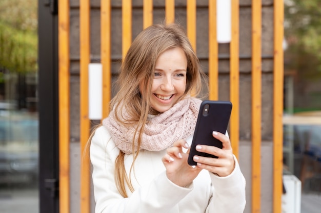 Giovane donna di affari sorridente in camice facendo uso dello smartphone