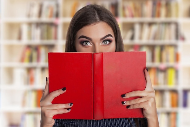 Giovane donna di bellezza con i libri in biblioteca