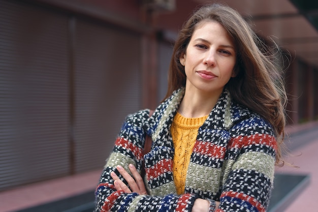 Giovane donna di braccia incrociate che indossa un cappotto di tweed in posa