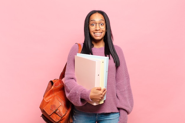 Giovane donna di colore che sembra felice e piacevolmente sorpresa, eccitata da un'espressione affascinata e scioccata. concetto di studente