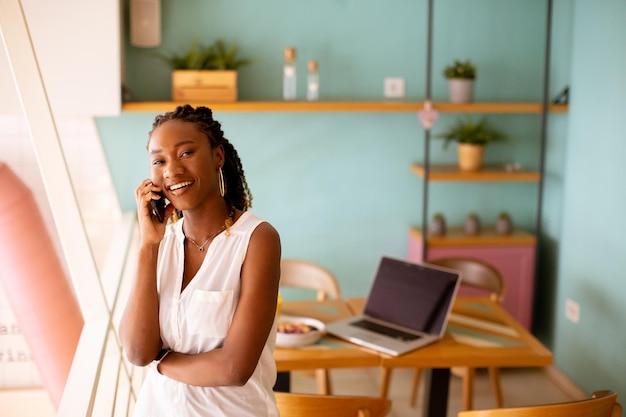 Giovane donna di colore che utilizza il telefono cellulare nella caffetteria