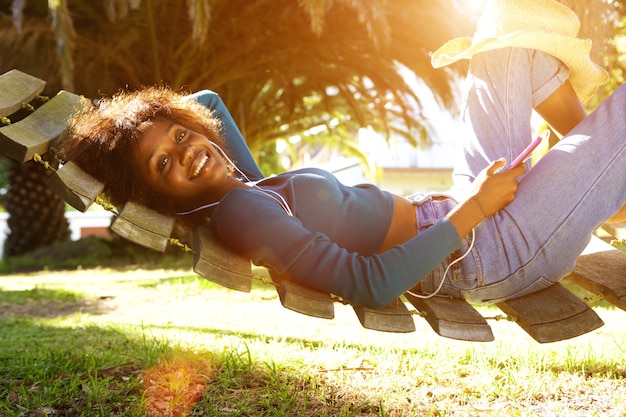 Giovane donna di colore sorridente che ascolta la musica con lo Smart Phone