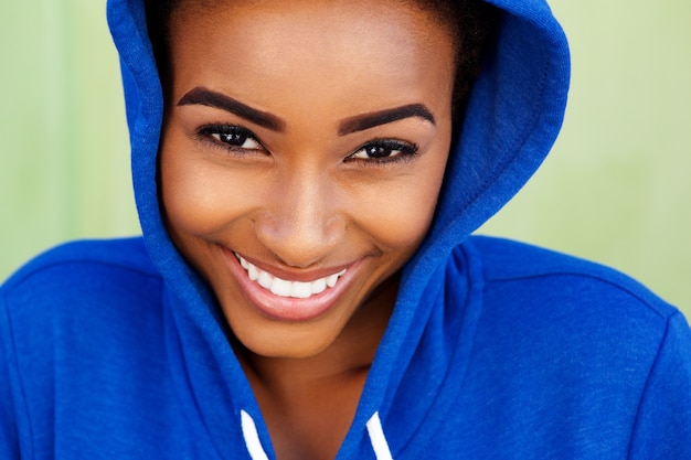Giovane donna di colore sorridente con la maglietta felpata blu