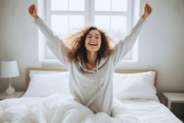 giovane donna di energia giovanile sul letto con le braccia in aria e sorridente