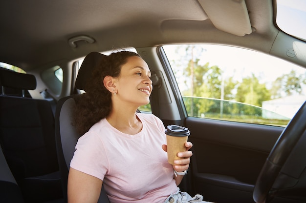 Giovane donna di etnia afroamericana che si gode la pausa caffè nella sua auto durante la sosta