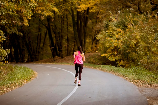 Giovane donna di forma fisica che funziona alla traccia della foresta