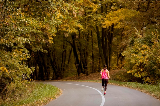 Giovane donna di forma fisica che funziona alla traccia della foresta