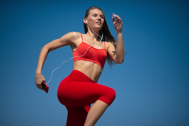 Giovane donna di forma fisica che funziona sul backround del cielo. Il concetto di uno stile di vita sano