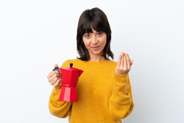 Giovane donna di razza mista azienda caffettiera isolata su sfondo bianco invitando a venire con la mano Felice che tu sia venuto