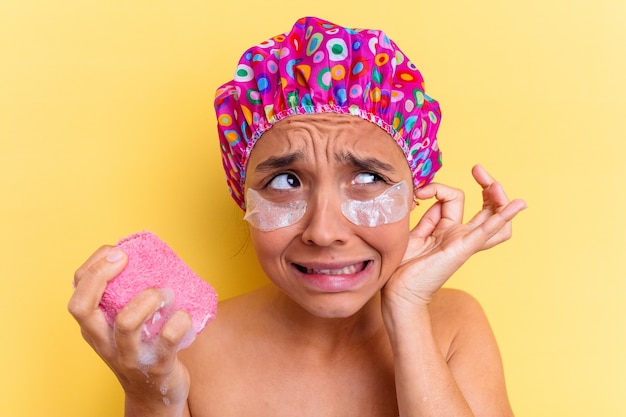 Giovane donna di razza mista che fa il bagno tenendo una spugna con una benda sotto gli occhi
