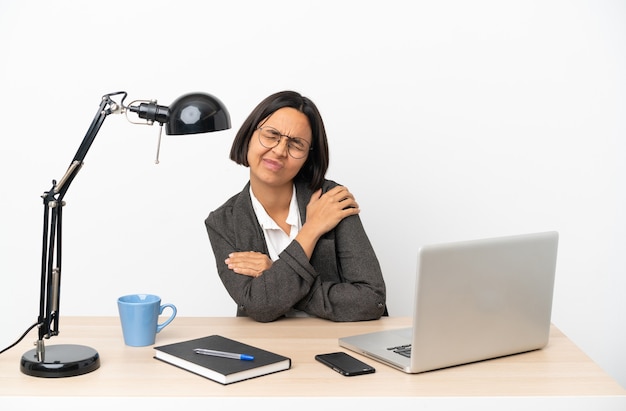 Giovane donna di razza mista che lavora in ufficio soffre di dolore alla spalla per aver fatto uno sforzo