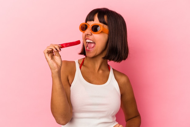 Giovane donna di razza mista che mangia e lecca un gelato isolato