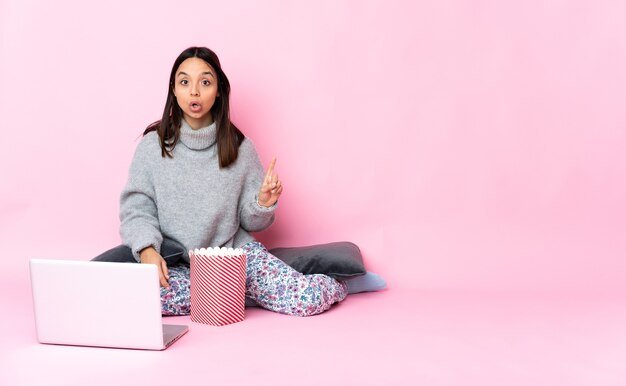 Giovane donna di razza mista che mangia popcorn