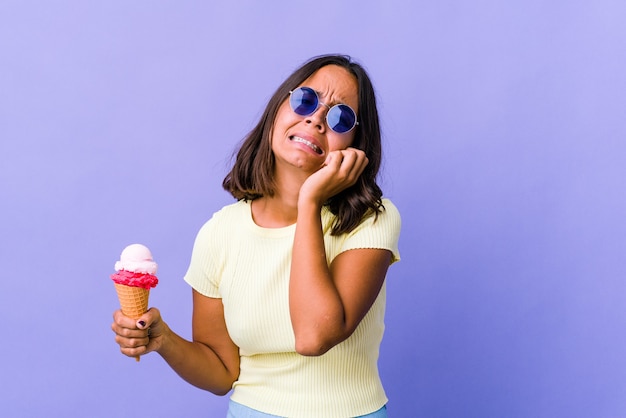 Giovane donna di razza mista che mangia un gelato piagnucolando e piangendo sconsolato.