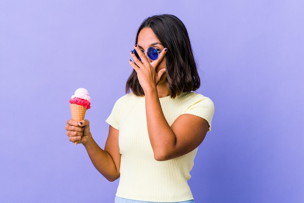 Giovane donna di razza mista che mangia un gelato sbatte le dita spaventata e nervosa.