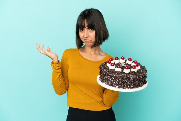 Giovane donna di razza mista che tiene in mano una torta di compleanno che ha dubbi?