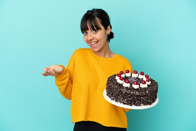 Giovane donna di razza mista che tiene in mano una torta di compleanno che ha dubbi?