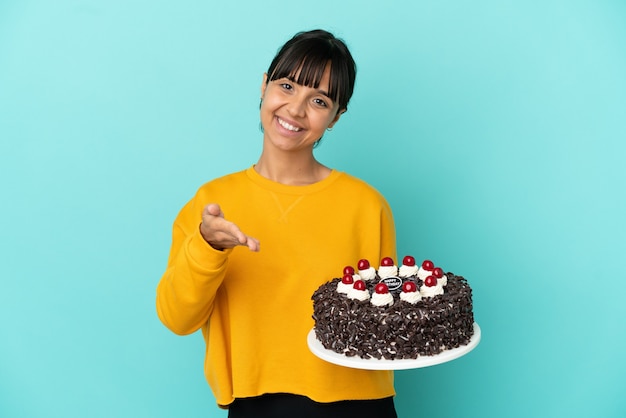 Giovane donna di razza mista che tiene la torta di compleanno che stringe la mano per aver chiuso un buon affare