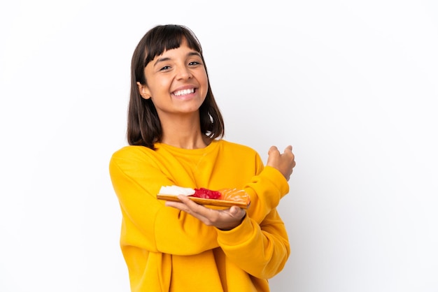 Giovane donna di razza mista che tiene sashimi isolato su sfondo bianco che punta indietro