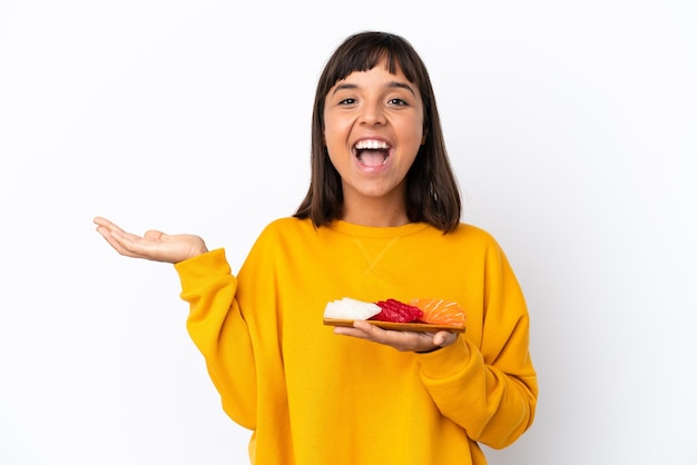 Giovane donna di razza mista che tiene sashimi isolato su sfondo bianco con espressione facciale scioccata