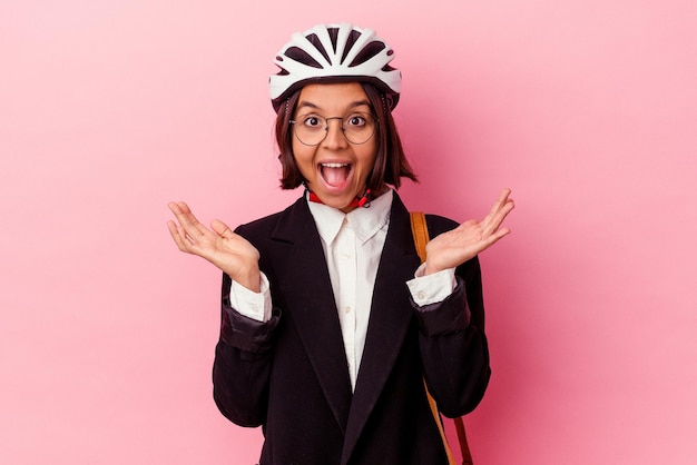 Giovane donna di razza mista d'affari che indossa un casco da bici isolato su sfondo rosa sorpreso e scioccato.