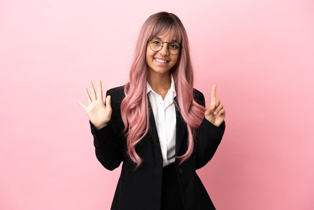 Giovane donna di razza mista d'affari con i capelli rosa isolata su sfondo rosa contando sei con le dita