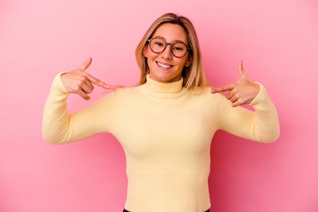 Giovane donna di razza mista isolata sul muro rosa punta verso il basso con le dita, sensazione positiva.