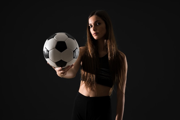 Giovane donna di sport che tiene un pallone da calcio